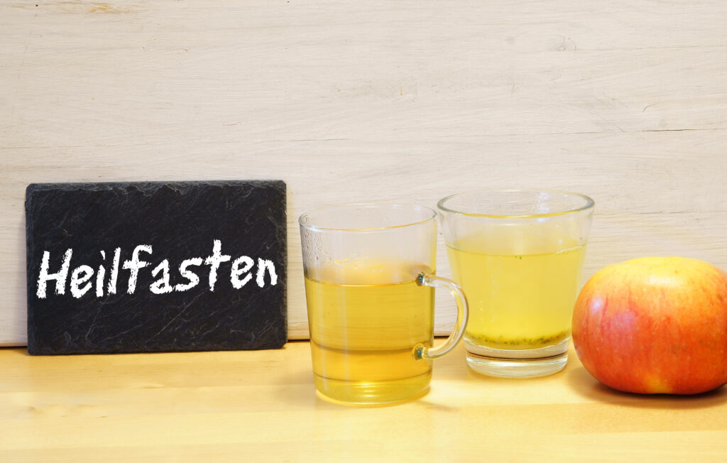Zwei Gläser mit Tee, ein Apfel, Schild mit Aufschrift Heilfasten