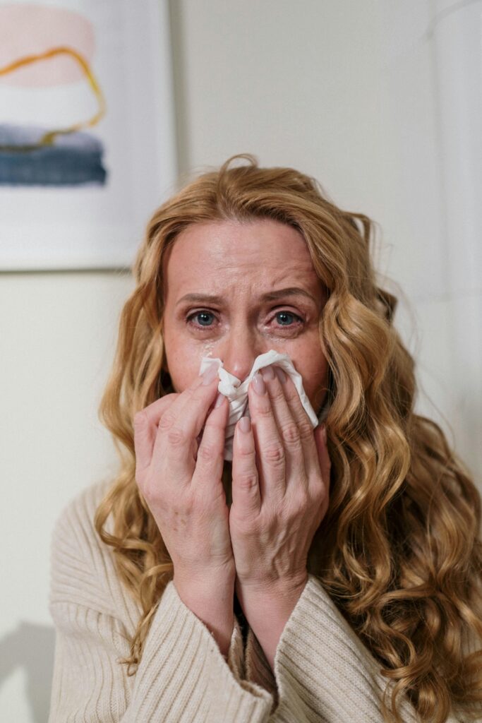 Frau mit Pollenallergie schnäuzt sich die Nase und hat verquollene Augen