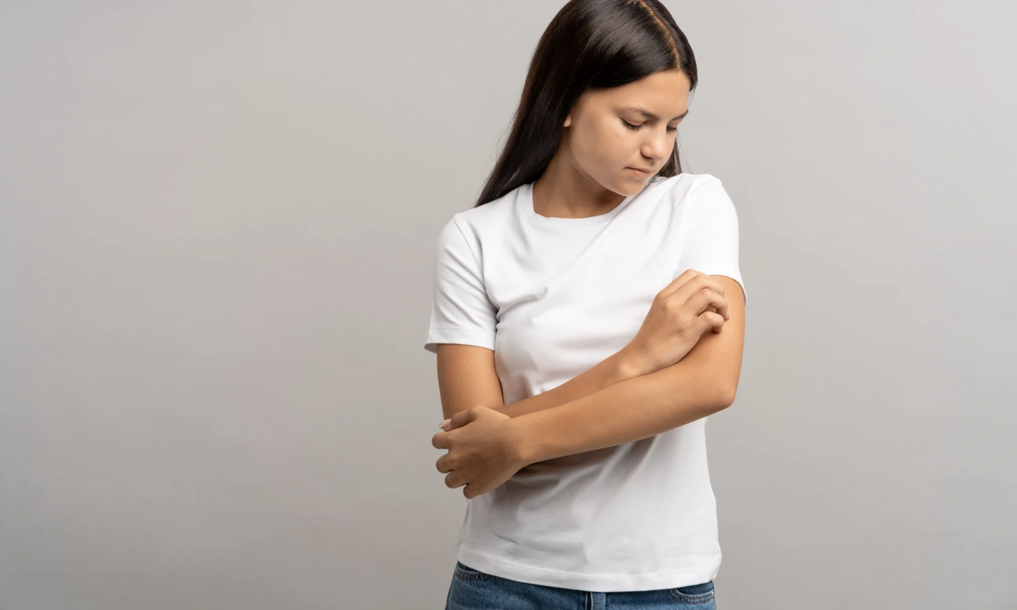 Mädchen mit Neurodermitis am Arm kratzt sich